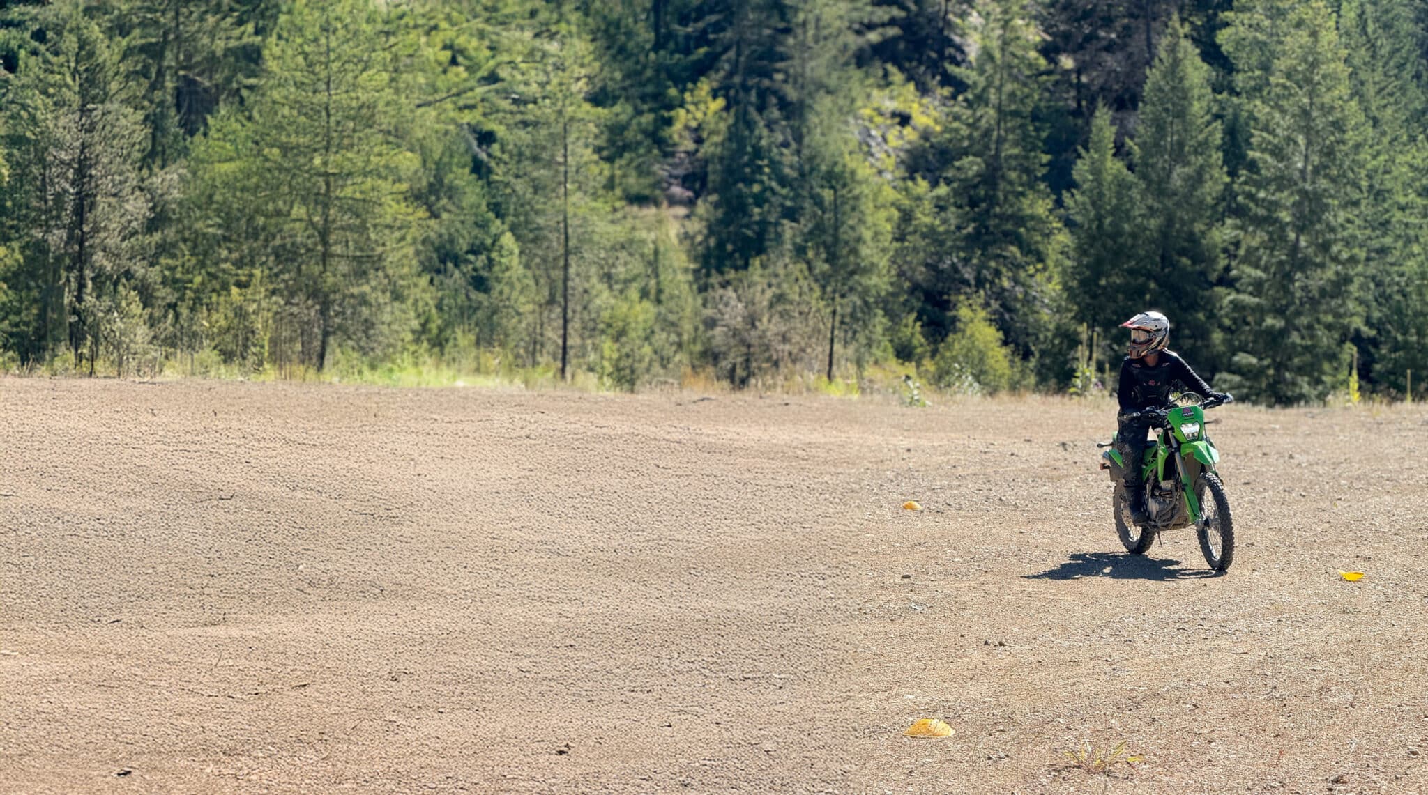 Cleared dirt area surrounded by green trees, ideal for outdoor activities or construction projects.