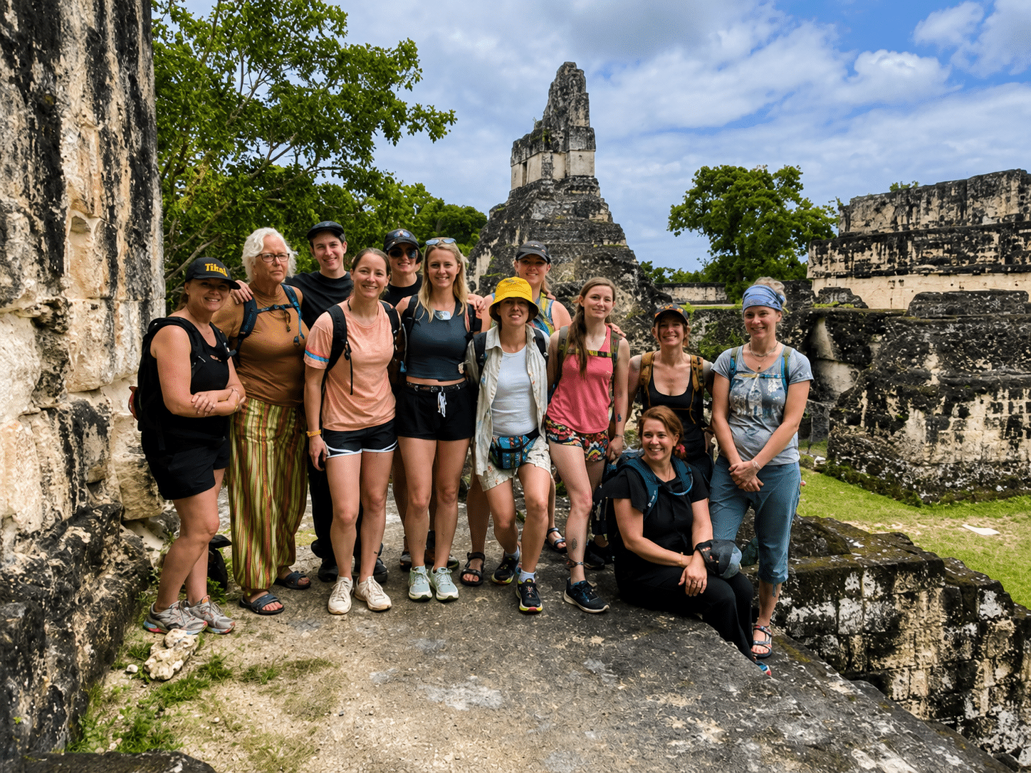 Group of tourists posing at ancient Mayan ruins in Tikal National Park, Guatemala on a sunny day.