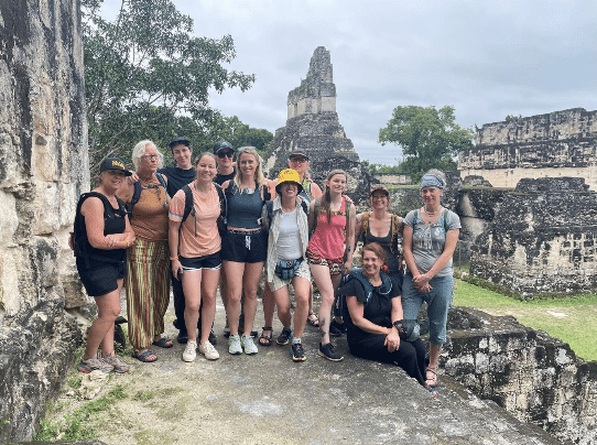 Group of tourists posing at ancient Mayan ruins in Tikal National Park, Guatemala.