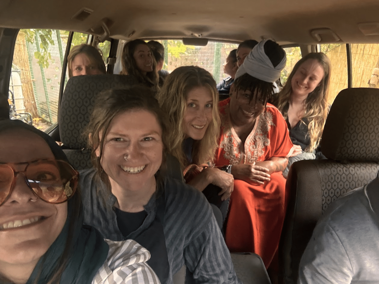 Group of diverse individuals smiling and enjoying a fun moment inside a vehicle, showcasing a friendly atmosphere during a trip or adventure.